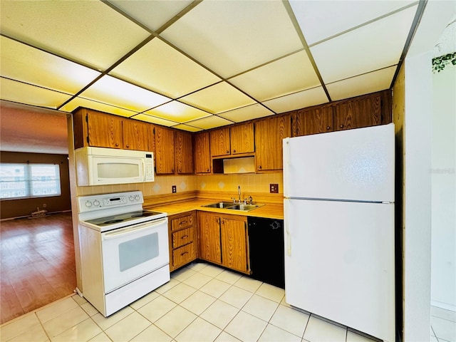 kitchen featuring a paneled ceiling, sink, light tile patterned floors, and white appliances