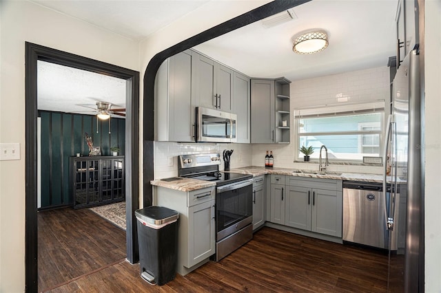 kitchen featuring light stone countertops, sink, dark wood-type flooring, gray cabinets, and appliances with stainless steel finishes