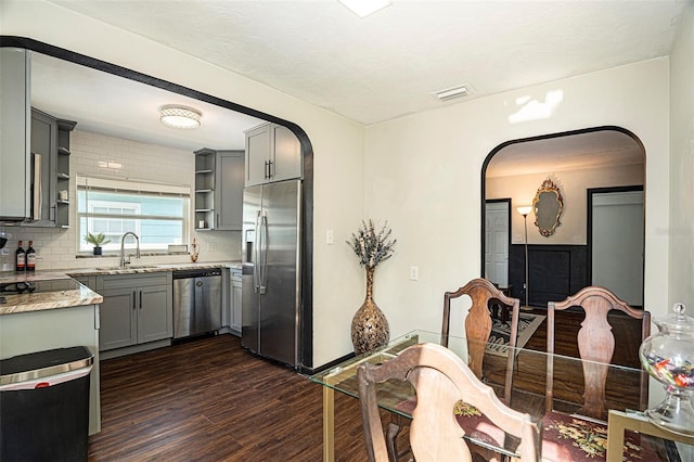 kitchen featuring gray cabinetry, sink, stainless steel appliances, dark hardwood / wood-style flooring, and decorative backsplash