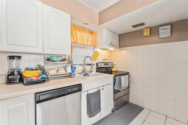 kitchen featuring white cabinetry, sink, light tile patterned flooring, tile walls, and appliances with stainless steel finishes