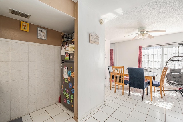 dining room featuring ceiling fan, tile walls, and light tile patterned flooring