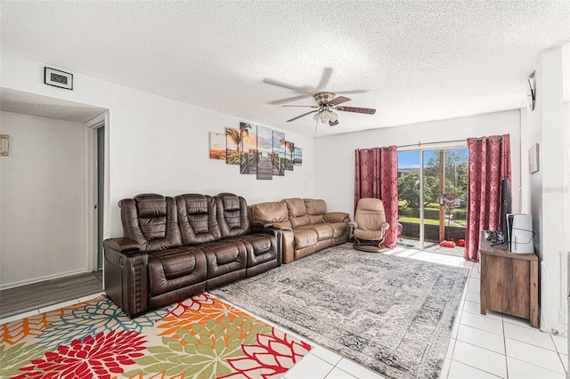 living room with ceiling fan, light tile patterned flooring, and a textured ceiling