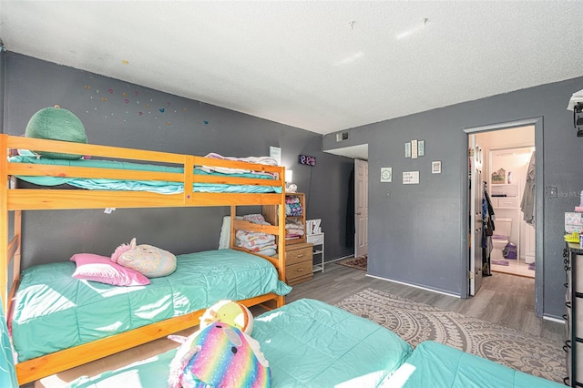 bedroom with ensuite bathroom, hardwood / wood-style floors, and a textured ceiling