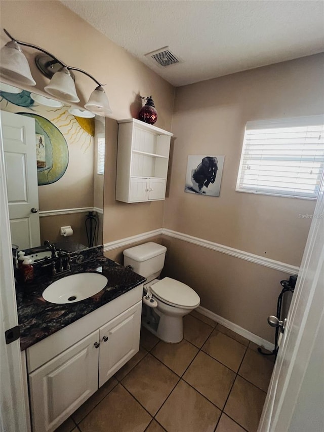 bathroom with tile patterned flooring, vanity, a textured ceiling, and toilet