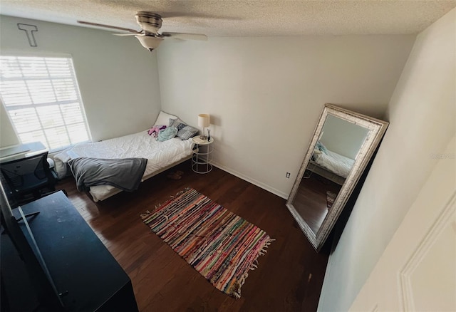 bedroom with dark wood-type flooring, ceiling fan, and a textured ceiling