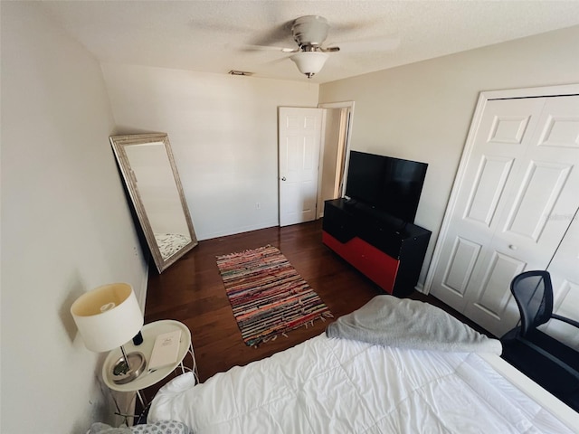 bedroom with a textured ceiling, dark hardwood / wood-style floors, a closet, and ceiling fan