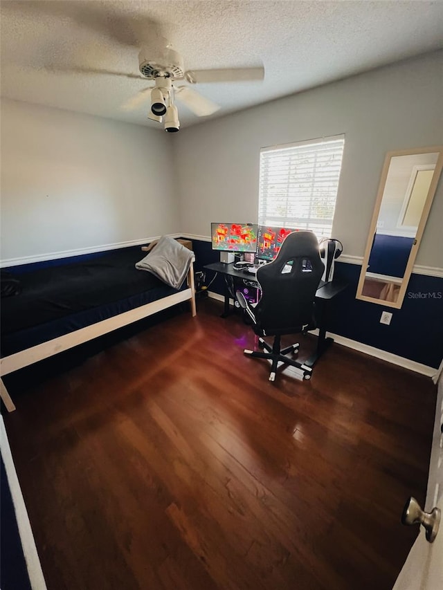 bedroom with hardwood / wood-style flooring, ceiling fan, and a textured ceiling