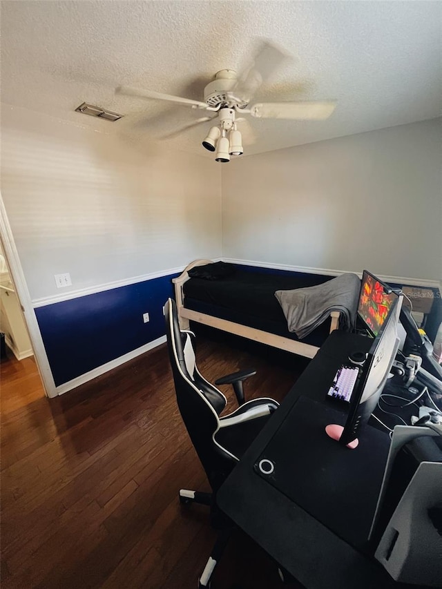 home office with ceiling fan, dark hardwood / wood-style floors, and a textured ceiling