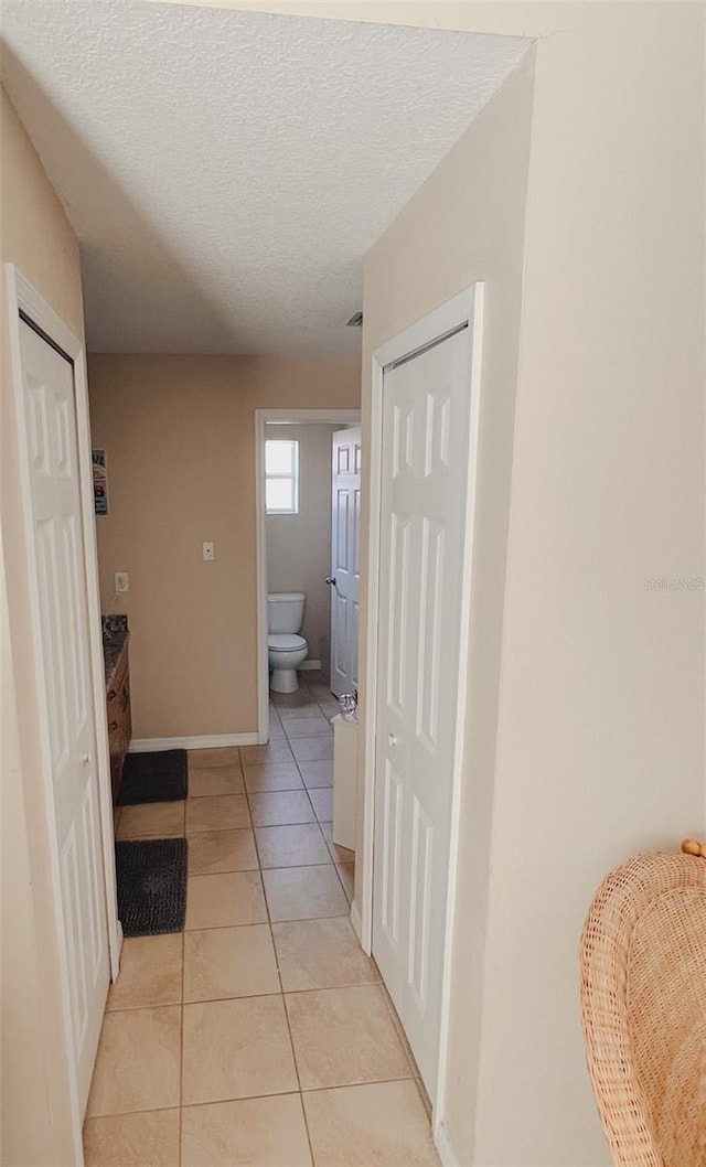 hallway with light tile patterned floors and a textured ceiling