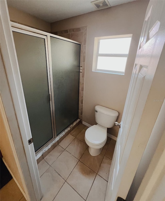 bathroom featuring tile patterned floors, toilet, and walk in shower