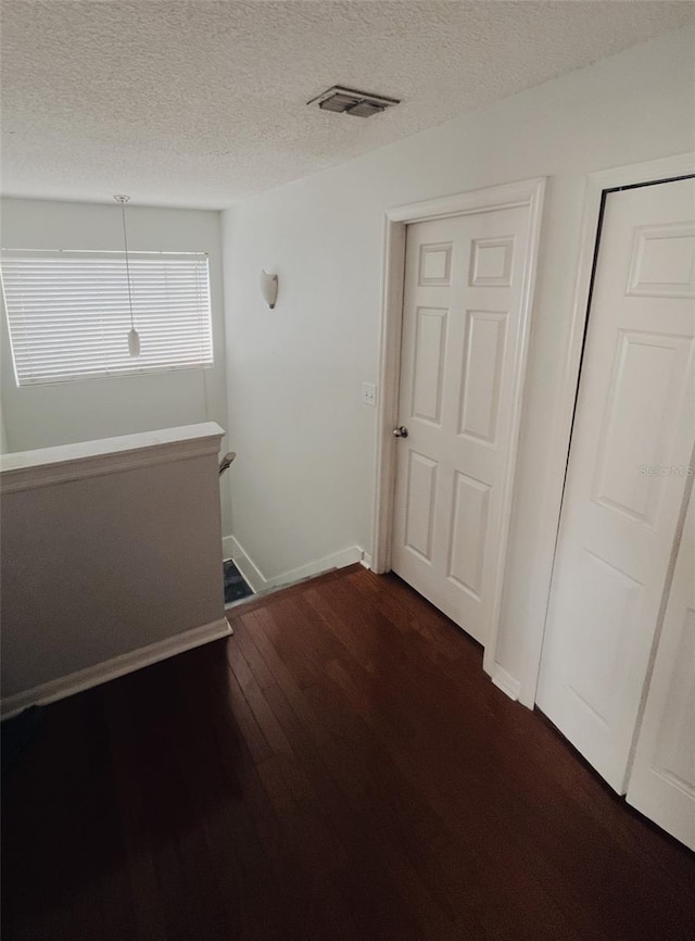 hall with dark hardwood / wood-style floors and a textured ceiling