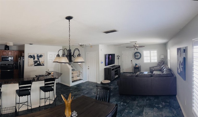 living room with visible vents, baseboards, and ceiling fan with notable chandelier