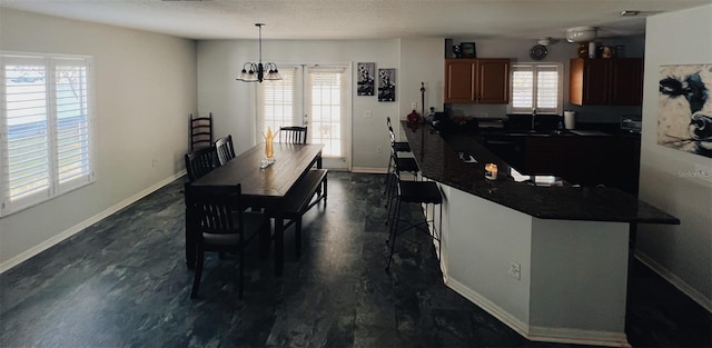 dining space featuring a notable chandelier, baseboards, dark wood finished floors, and a textured ceiling