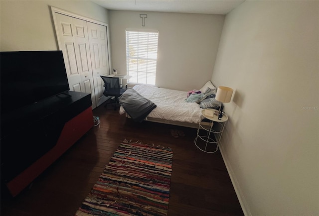 bedroom featuring a closet, baseboards, and dark wood-type flooring