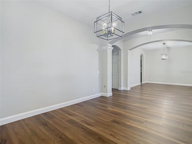 unfurnished dining area with dark hardwood / wood-style floors, an inviting chandelier, and ornate columns