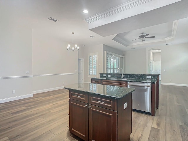 kitchen with stainless steel dishwasher, a center island, dark stone countertops, and light wood-type flooring