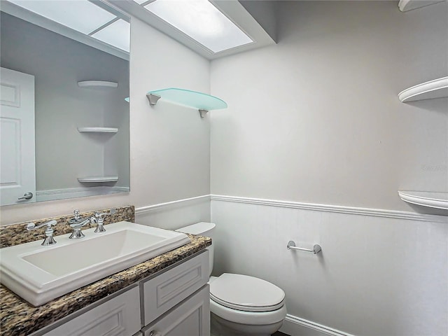 bathroom with a skylight, vanity, and toilet