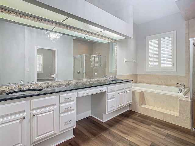 bathroom featuring plus walk in shower, hardwood / wood-style floors, vanity, and a notable chandelier