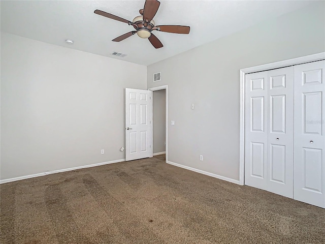 unfurnished bedroom with ceiling fan, a closet, and dark colored carpet