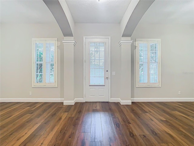 foyer with ornate columns and dark wood-type flooring