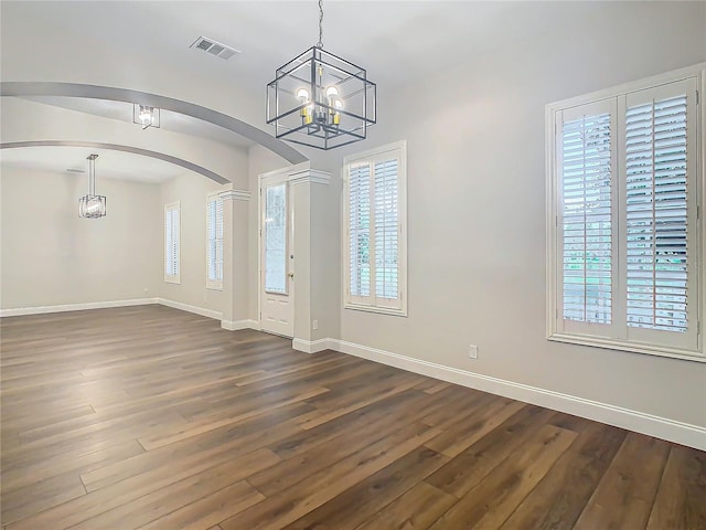 10130 Balcony St, New Port Richey, FL 34655 - unfurnished dining area with arched walkways, a chandelier, plenty of natural light, and dark wood-type flooring