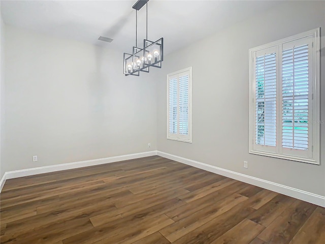 unfurnished dining area with dark wood-type flooring and an inviting chandelier