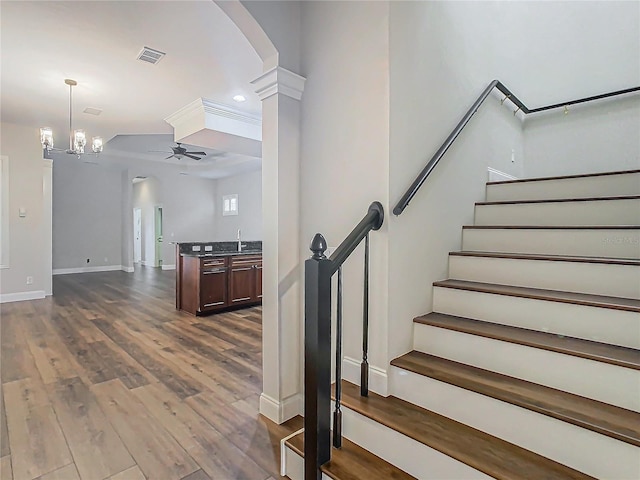 stairs featuring wood-type flooring and ceiling fan with notable chandelier