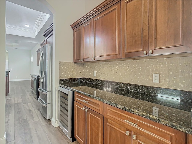 kitchen featuring dark stone counters, beverage cooler, crown molding, light hardwood / wood-style flooring, and stainless steel refrigerator