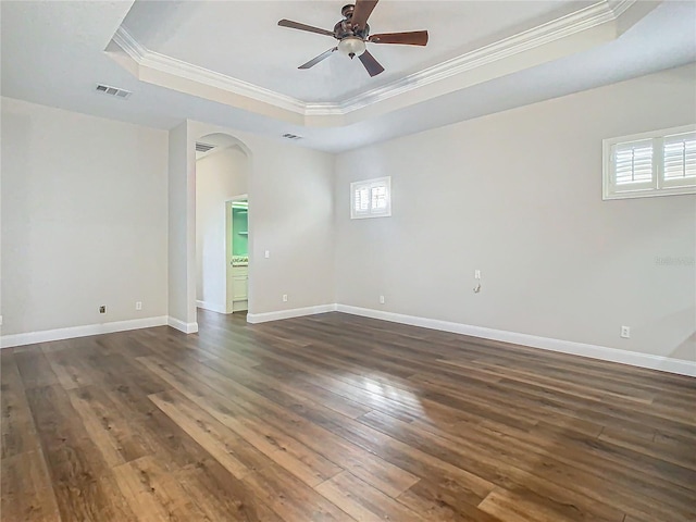 empty room featuring ceiling fan, ornamental molding, dark wood-type flooring, and a tray ceiling