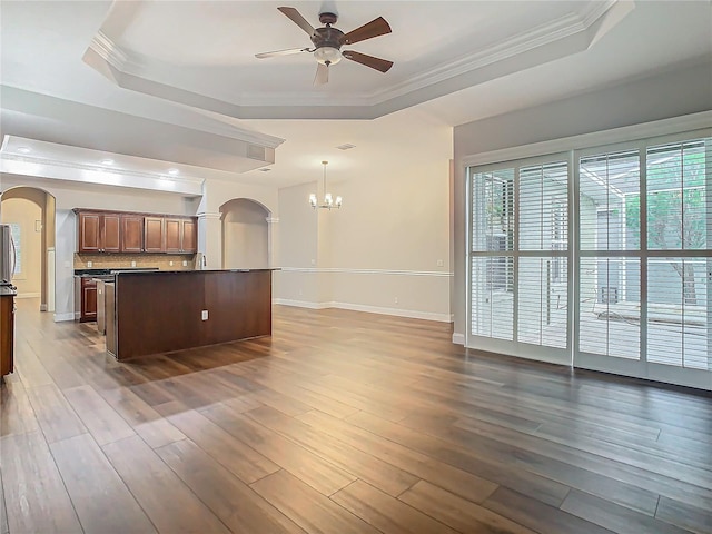 kitchen with ceiling fan with notable chandelier, dark hardwood / wood-style flooring, decorative light fixtures, and a raised ceiling