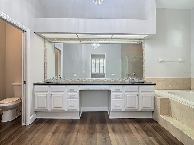 full bathroom featuring vanity, toilet, wood-type flooring, and shower with separate bathtub