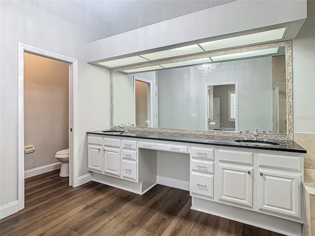 bathroom with hardwood / wood-style floors, vanity, a shower with door, toilet, and a chandelier