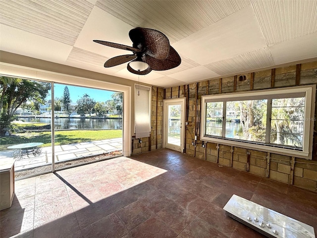 unfurnished sunroom featuring ceiling fan, a healthy amount of sunlight, and a water view