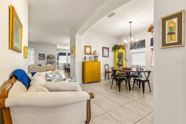 tiled living room featuring a healthy amount of sunlight and a notable chandelier