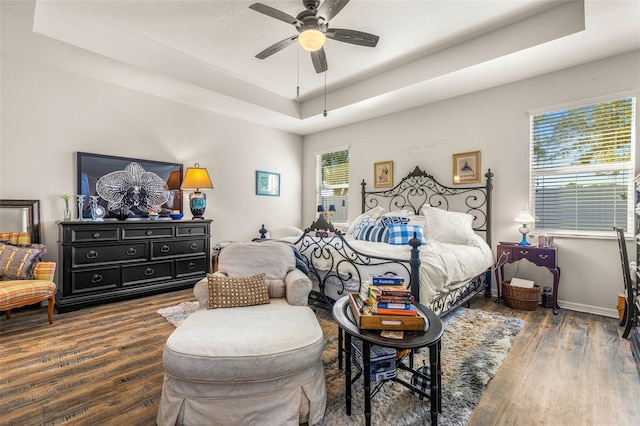 bedroom featuring a textured ceiling, ceiling fan, a raised ceiling, and dark wood-type flooring