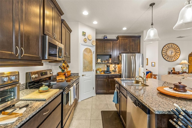 kitchen with sink, stainless steel appliances, light stone counters, decorative light fixtures, and light tile patterned flooring