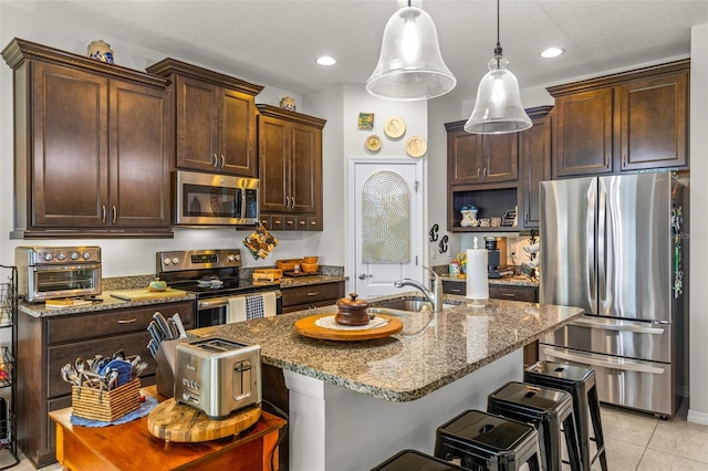 kitchen featuring appliances with stainless steel finishes, light stone counters, sink, light tile patterned floors, and decorative light fixtures