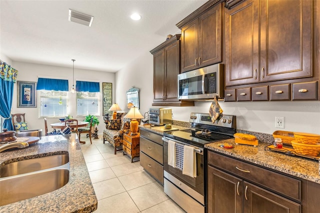 kitchen with light stone countertops, stainless steel appliances, sink, light tile patterned floors, and hanging light fixtures