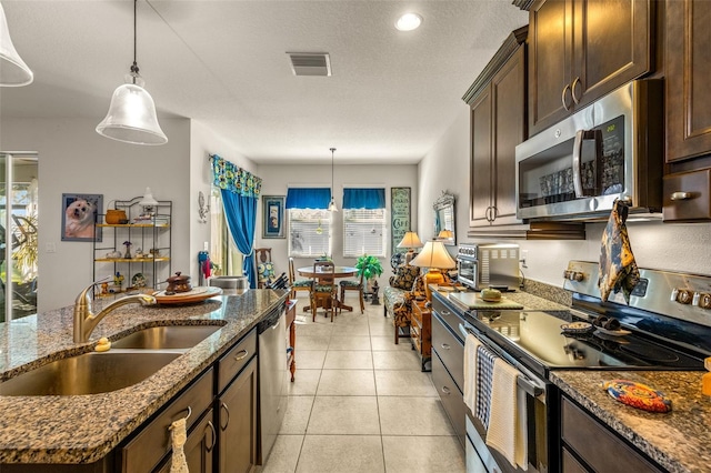 kitchen featuring dark brown cabinetry, sink, stainless steel appliances, and decorative light fixtures