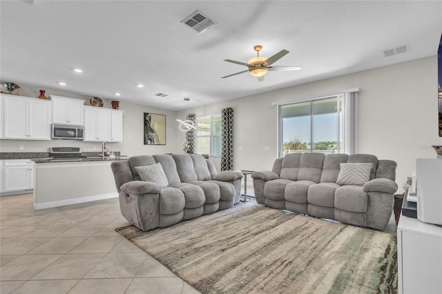 living room featuring light tile patterned floors, a textured ceiling, sink, and ceiling fan