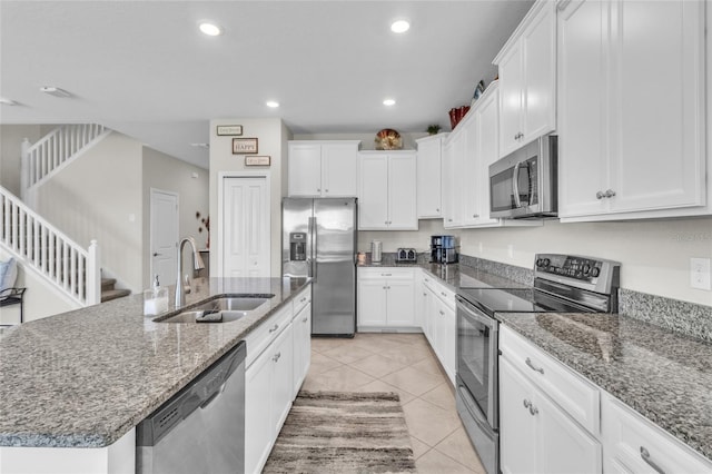 kitchen with stainless steel appliances, white cabinetry, sink, and a kitchen island with sink