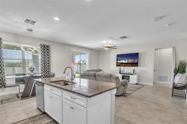 kitchen featuring sink, dishwasher, dark stone countertops, an island with sink, and white cabinets