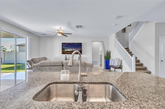 kitchen featuring ceiling fan, stone countertops, and sink