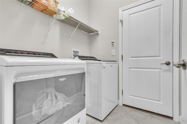 clothes washing area featuring washing machine and dryer and light tile patterned floors