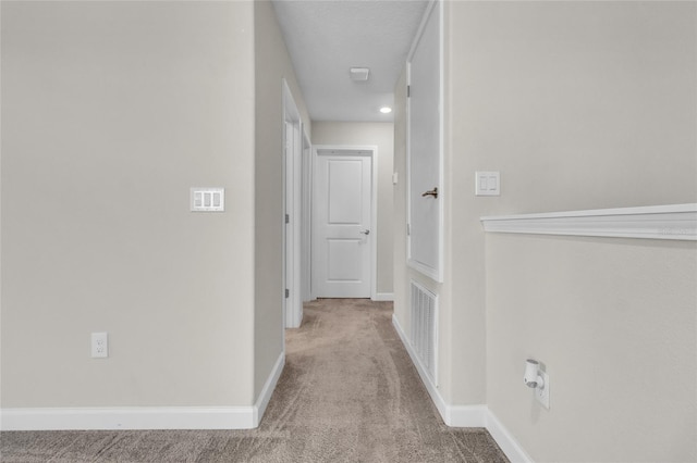 hall featuring light carpet and a textured ceiling