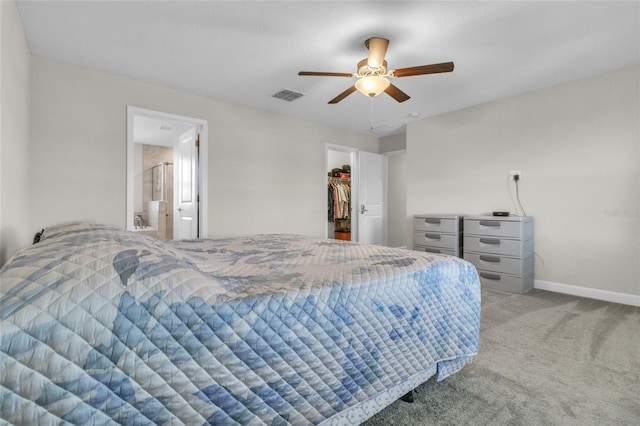 carpeted bedroom with ceiling fan, a walk in closet, ensuite bathroom, and a closet