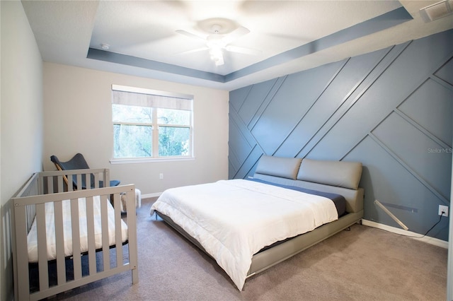 bedroom with carpet floors, a raised ceiling, and ceiling fan