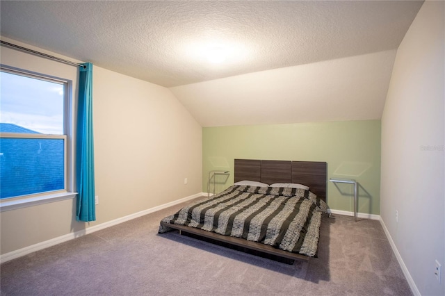 bedroom with a textured ceiling, carpet, and vaulted ceiling