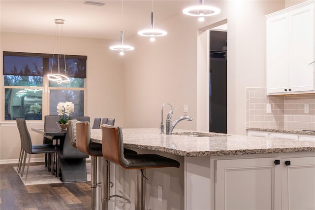 kitchen with pendant lighting, dark hardwood / wood-style floors, decorative backsplash, and white cabinetry