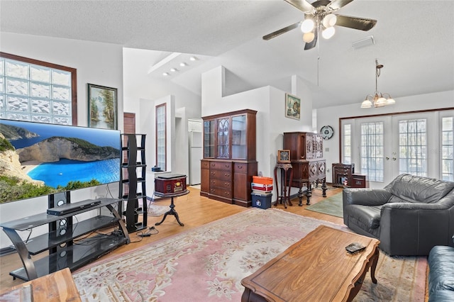 living room featuring plenty of natural light, light hardwood / wood-style floors, french doors, and vaulted ceiling